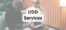 Two people sitting together and talking in a supportive setting, with the text "I/DD Services" displayed. 
