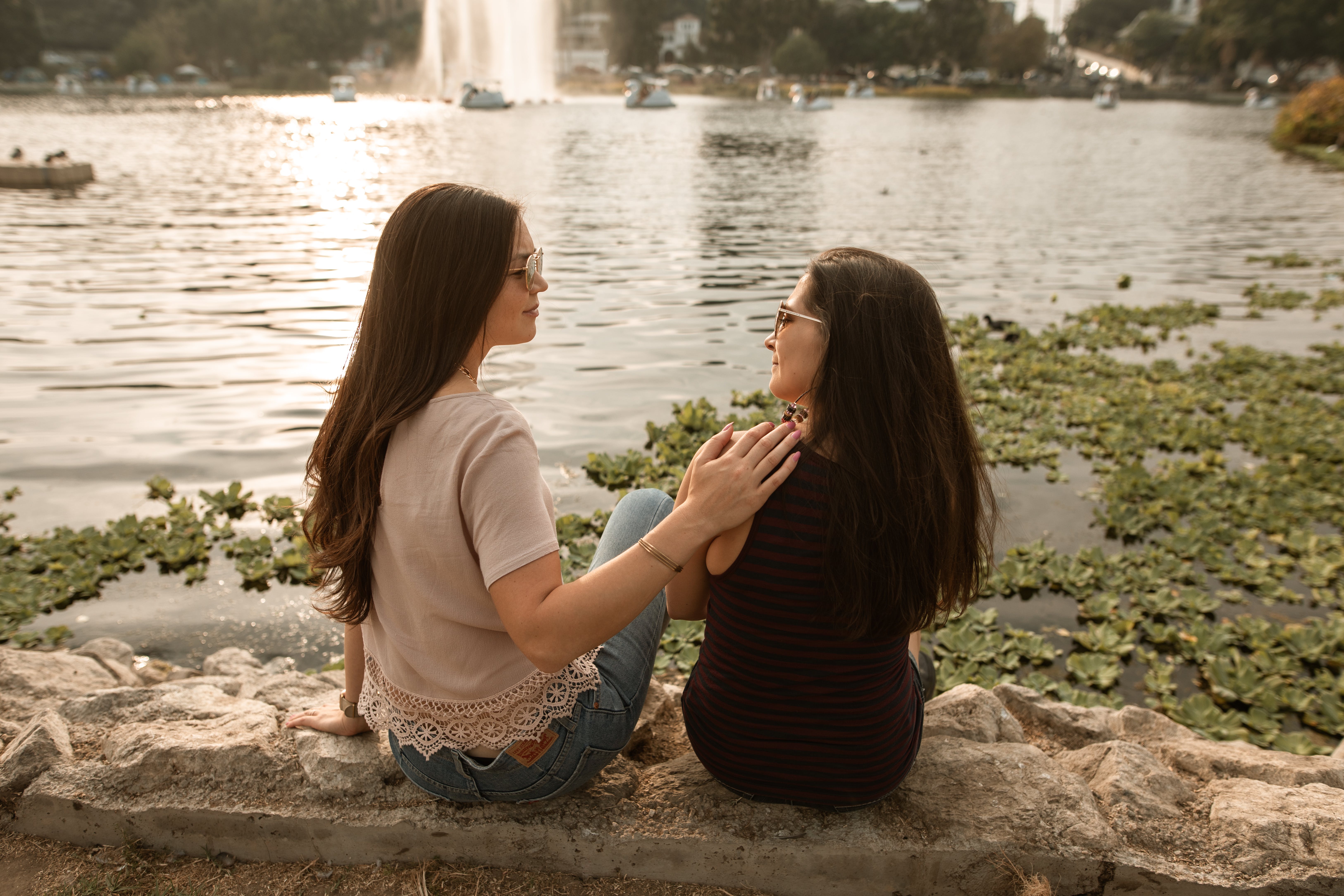 two women sitting by lake