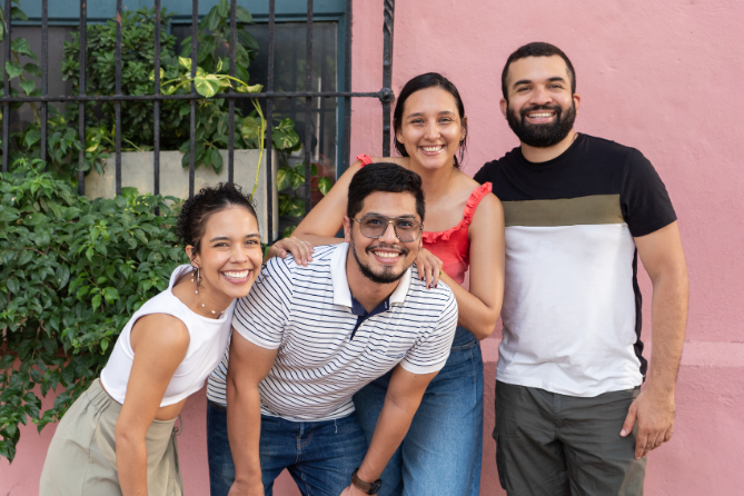 Four people standing together outdoors smiling 