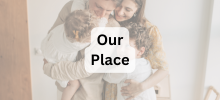 Two adults embracing two young children in a warm indoor setting, showing a close family moment with "Our Place" text displayed.