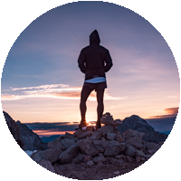 Person standing on cliff at sunset