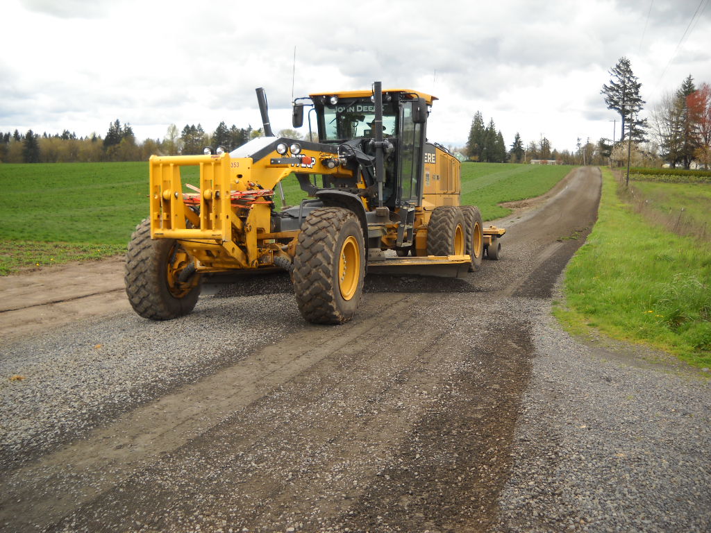 Grader applying gravel to road